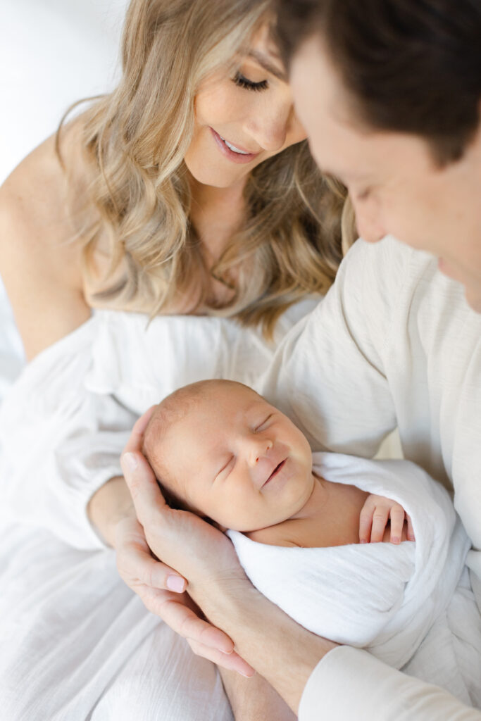 Baby smiling in arms of mother and father